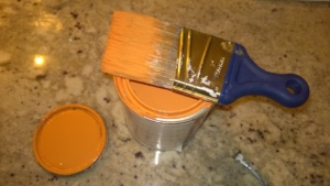 orange paint can and wooster shortcut brush on counter
