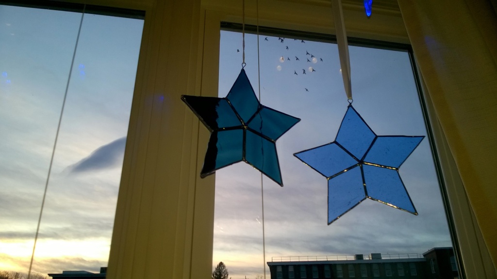 blue and teal stained glass stars hanging in living room window