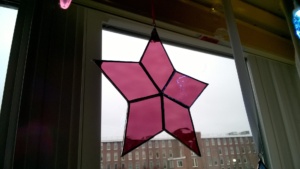 raspberry stained glass star hanging in living room window