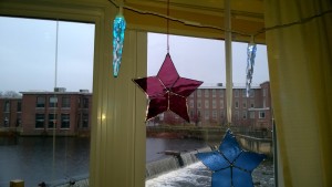 raspberry and blue stained glass stars hanging in living room window