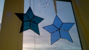 diy stained glass stars hanging in living room window with birds flying by