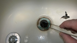 using huge tweezers to pull hair out of the shower drain