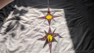 the completed pink and yellow nautical stained glass star reflected on the bed